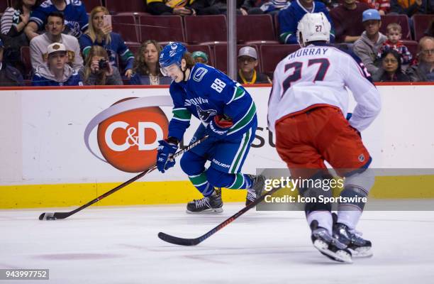 Vancouver Canucks Center Adam Gaudette handles the puck behind Columbus Blue Jackets Defenceman Ryan Murray during the third period in a NHL hockey...