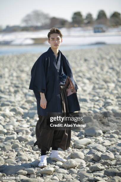 a young man dressing up and standing in a riverbank - kimono winter stock pictures, royalty-free photos & images