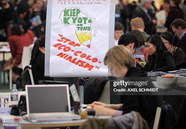 Participants of the United Nations Climate Change Conference sit in front of a placard at the Bella Centre in Copenhagen on December 14, 2009....