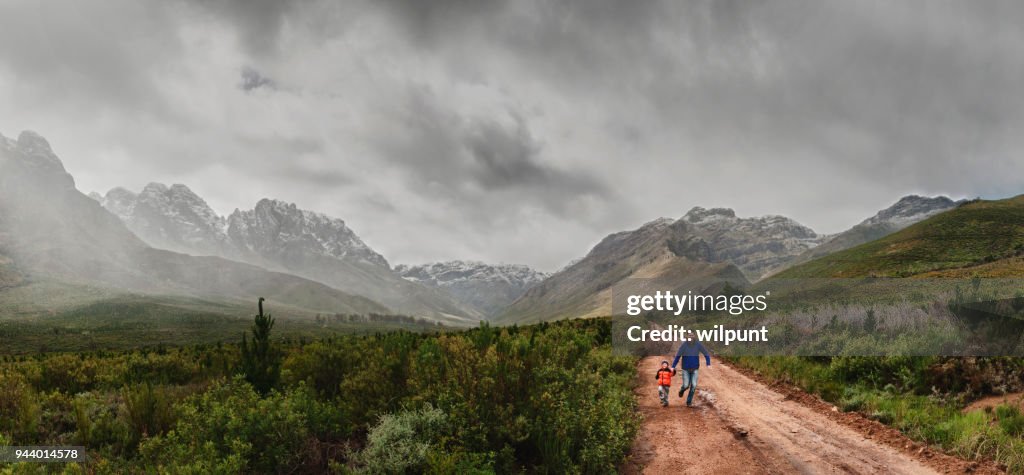 Father and Son Running Together between snow capped mountains