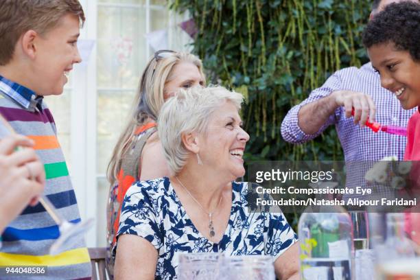 grandmother talking to boy (8 to 9 years) at multi generation lunch on garden patio - 50 54 years stockfoto's en -beelden