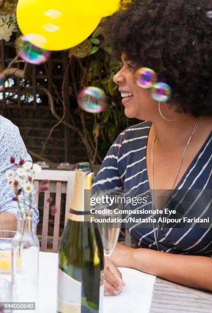 smiling woman enjoying lunch on garden patio with friends and champagne - brinco charm - fotografias e filmes do acervo