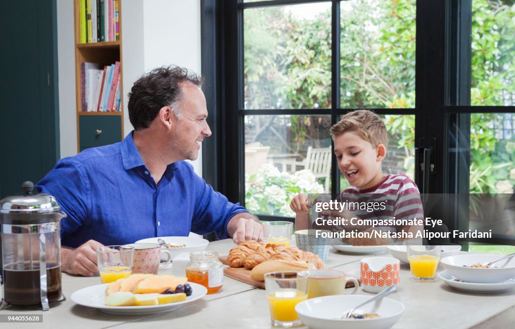 Father and son having breakfast at dining table