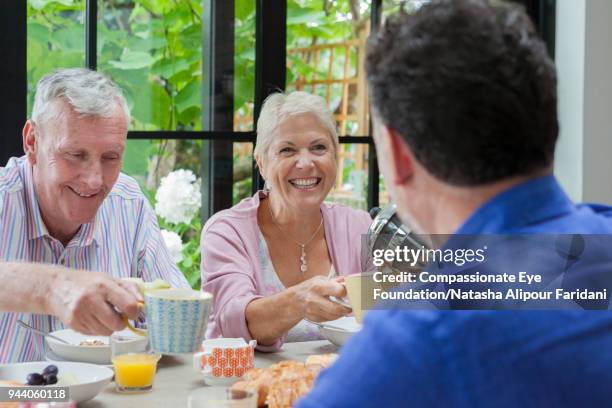 multi generation family having breakfast at dining table - juice pour stock pictures, royalty-free photos & images
