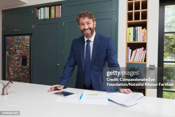 smiling financial advisor with digital tablet and paperwork in kitchen - fiduciary responsibility stock pictures, royalty-free photos & images