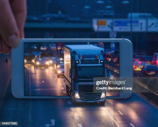 mobile phone displaying a truck driving through the phone - augmented reality stock-fotos und bilder