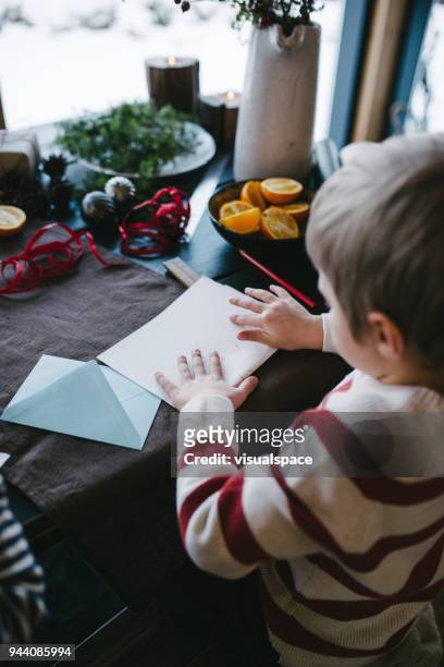 boy wraps a letter to santa claus - child writing letter to santa stock pictures, royalty-free photos & images