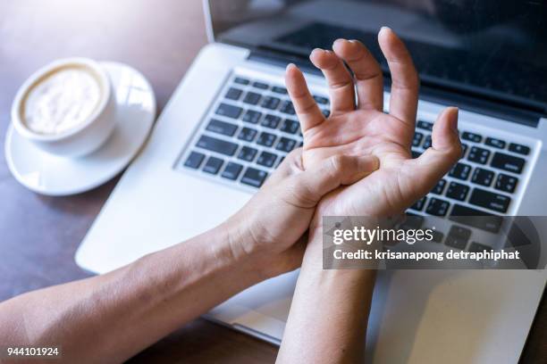 work on the notebook wrist pain,hand pain,wrist pain - sehnenscheidenentzündung stock-fotos und bilder