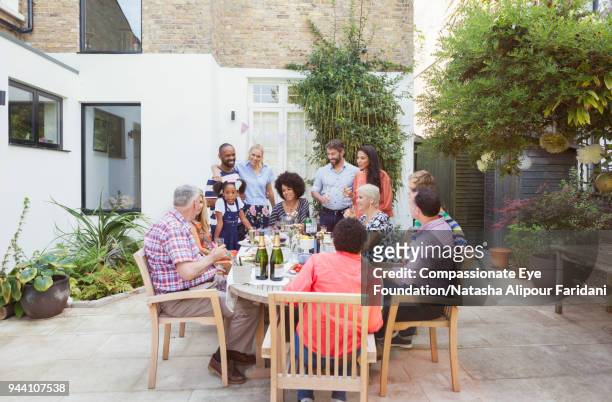 multi generation family enjoying birthday party at patio table - 40 birthday foto e immagini stock