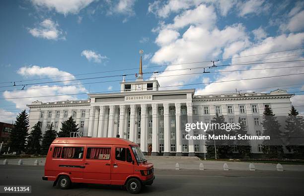 Red bus passes the House of Soviets on October 19, 2008 in Tiraspol, Moldova. Tiraspol is the second largest city in Moldova and is the capital and...