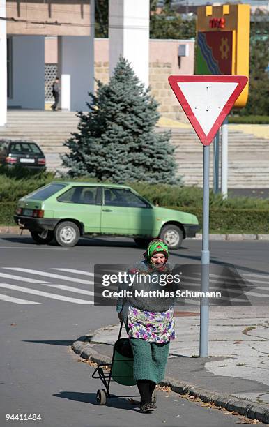 An old woman crosses a street on October 19, 2008 in Tiraspol, Moldova. Tiraspol is the second largest city in Moldova and is the capital and...