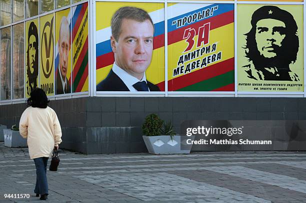 Woman passes the office of a transnistrian youth organisation showing the faces of the former Russian President Vladimir Putin, the current President...