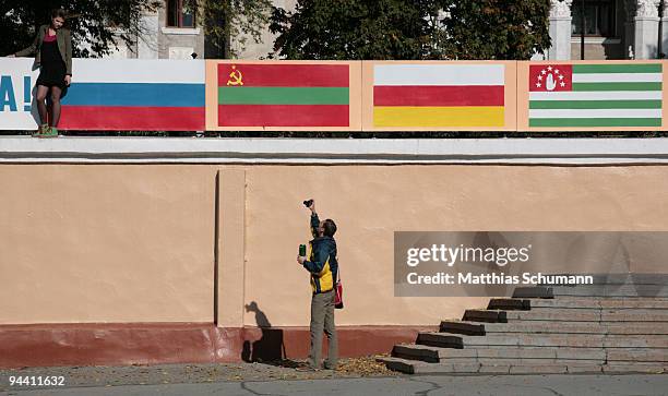 Man photographs his girlfriend in front of the flags of Russia, Transnistria, South Ossetia and Abkhazia in Tiraspol in the Transnistria region in...