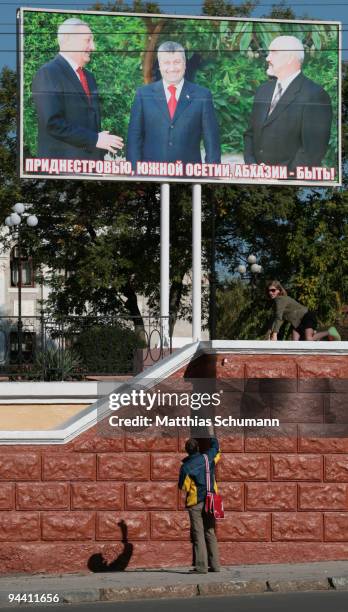 Man photographs his girlfriend in front of a billboard showing the Presidents of Transnistria, South Ossetia and Abkhazia in the center of Tiraspol...
