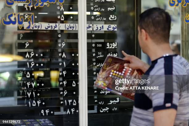 Iranians check exchange rates outside a bank in the capital Tehran on April 10, 2018. Iran took the drastic step of fixing the rate of its currency...
