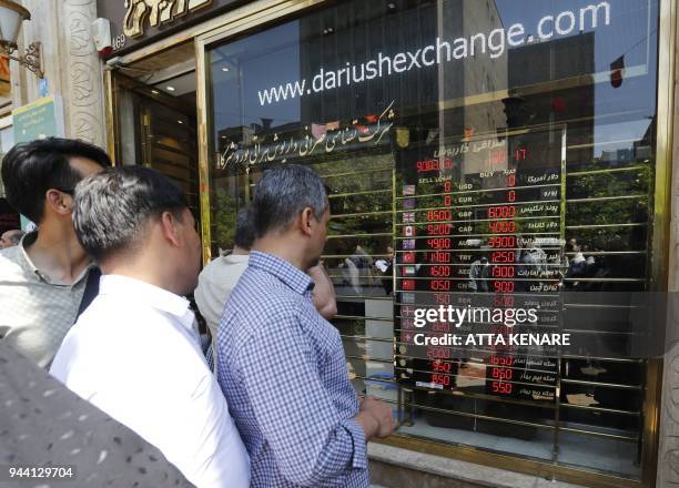 Iranians check exchange rates outside a bank in the capital Tehran on April 10, 2018. Iran took the drastic step of fixing the rate of its currency...