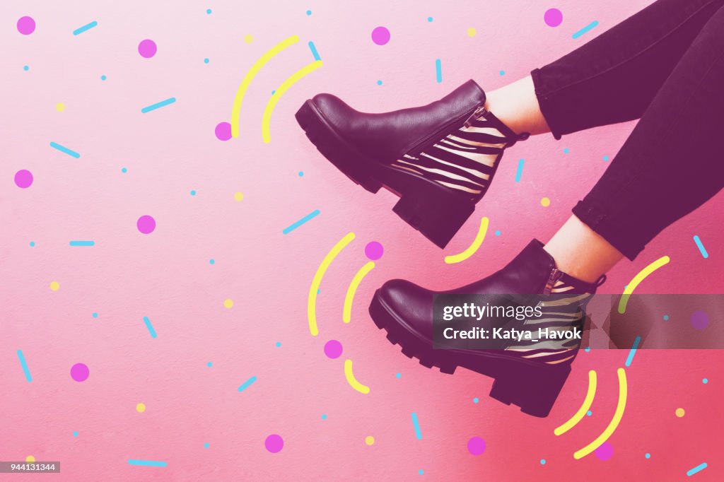 Two women's legs dangle in fashionable boots.