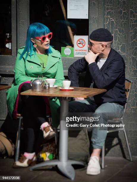 couple in colorful clothes chatting outside cafe - gary colet stock pictures, royalty-free photos & images