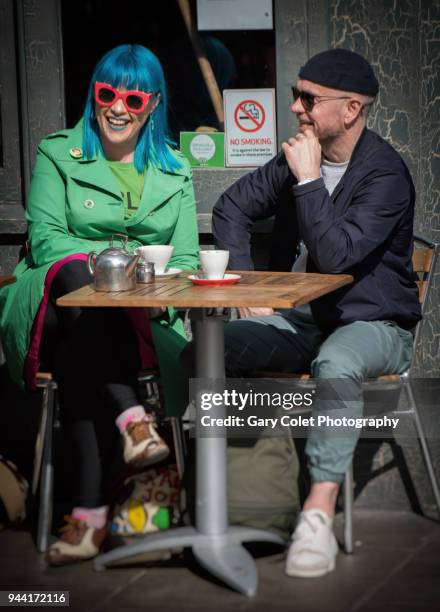 couple in colorful clothes talking and laughing outside a cafe - gary colet stock pictures, royalty-free photos & images