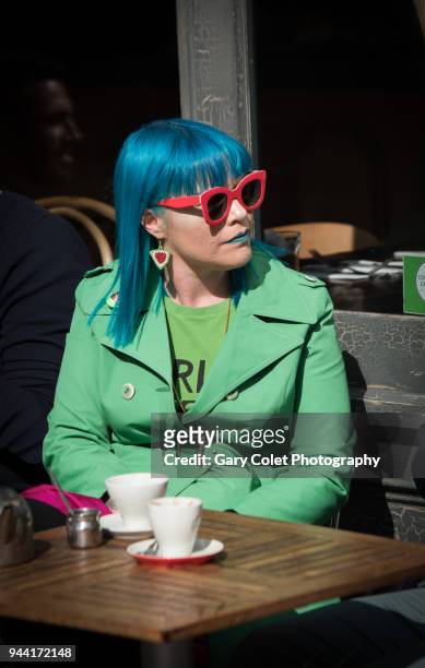 woman in bright green coat and blue hair outside cafe - gary colet stock pictures, royalty-free photos & images