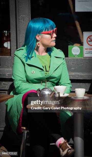 woman in bright green coat and blue hair outside cafe - gary colet stock pictures, royalty-free photos & images