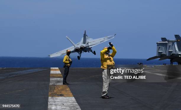 Sailors stand on the flight deck while an FA-18 hornet fighter jet takes off, during a routine training aboard US aircraft carrier Theodore Roosevelt...