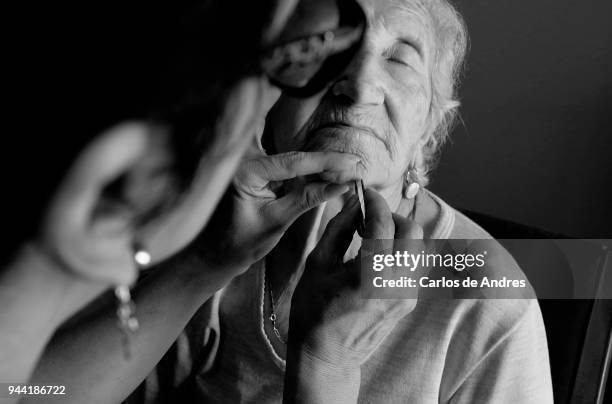 Social assistant is cleaning Maria Del Palacio 's face on August 30, 2016 in Madrid, Spain. Maria del Palacio, a ninety-five year old widow, resides...