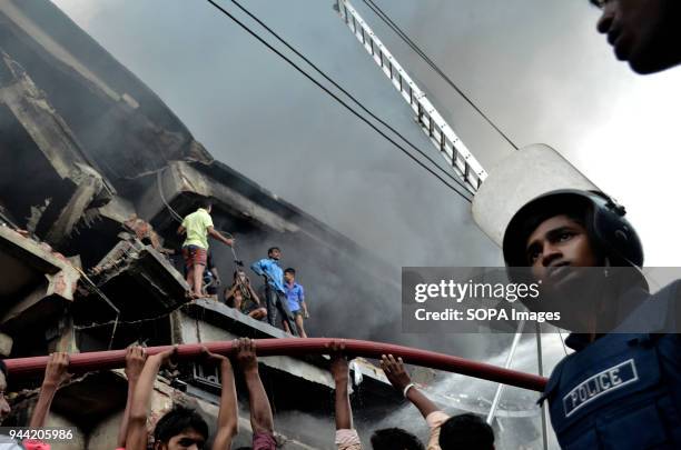 Policeman seen near the factory building as it was burning. At least 34 workers died in a fire that ripped through a factory in Bangladesh. The fire...