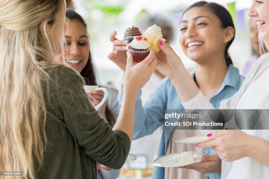 Women 'toast' with cupcakes during charity event