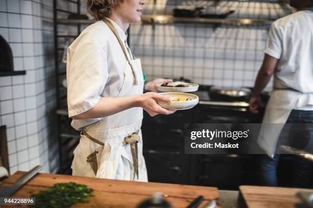 midsection of waitress carrying food plates in kitchen at restaurant - carrying food stock pictures, royalty-free photos & images