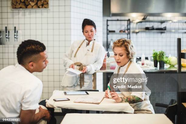 multi-ethnic owners discussing while sitting at table in restaurant - chef team stock pictures, royalty-free photos & images