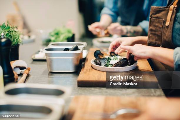 midsection of female chefs preparing food on counter in restaurant kitchen - mussels stockfoto's en -beelden