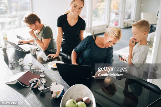 high angle view of family using technologies at dining table in room - 45 couple stockfoto's en -beelden