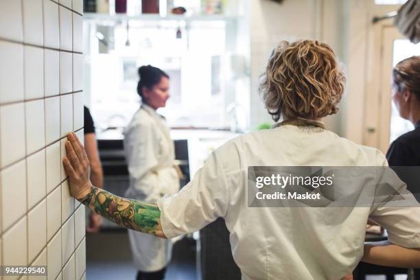 rear view of chef standing with female colleagues in restaurant kitchen - kokkin stockfoto's en -beelden