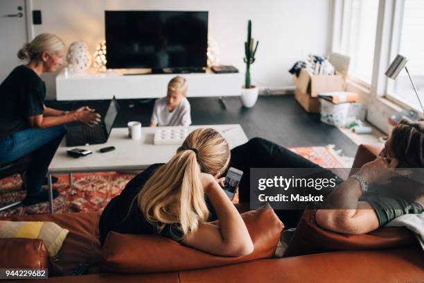 high angle view of family sitting in living room with technologies at home - tv internet phone stock pictures, royalty-free photos & images