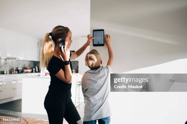 teenage girl talking on phone using digital tablet by brother standing at home - command sisters photos et images de collection