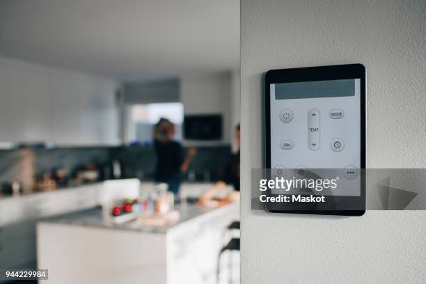 thermostat app on digital tablet mounted over white wall at home - smart kitchen fotografías e imágenes de stock
