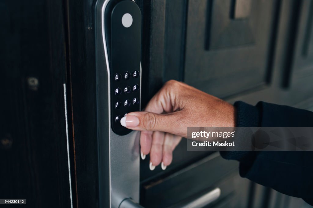Cropped hand of woman unlocking combination security code on house door