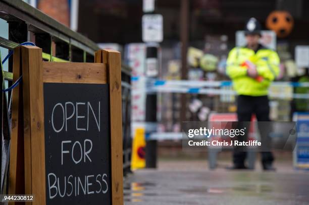 Sign showing local businesses are open next to police officers at a cordon near the scene where former double-agent Sergei Skripal and his daughter,...