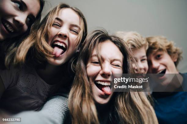 low angle view of cheerful friends at home - stick tongue out foto e immagini stock