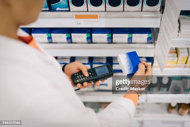 midsection of male pharmacist using bar code reader on medicine standing by rack at store - bar code reader 個照片及圖片檔