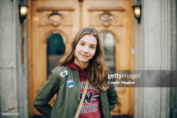 portrait of smiling girl standing against building - 12 13 jahre mädchen stock-fotos und bilder