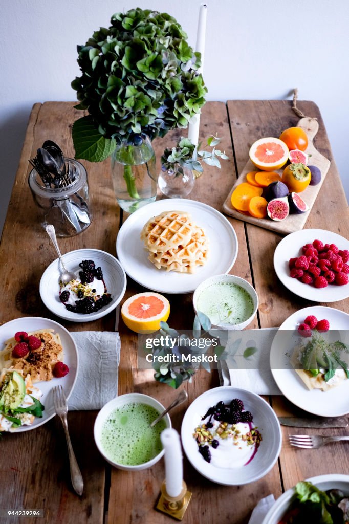 High angle view of various food on wooden table by wall