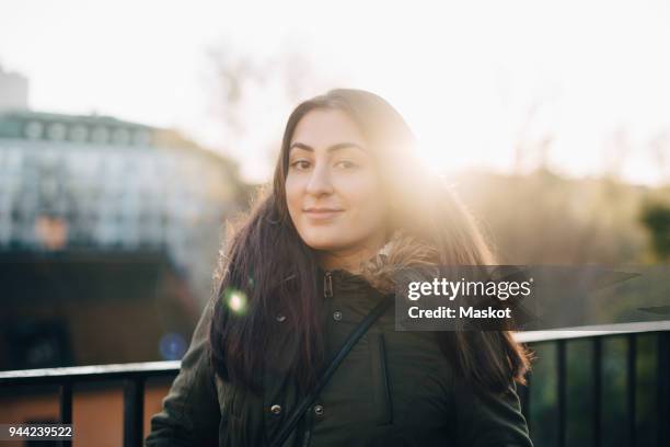 back lit portrait of confident young woman wearing warm clothing against sky - west asian people stock pictures, royalty-free photos & images
