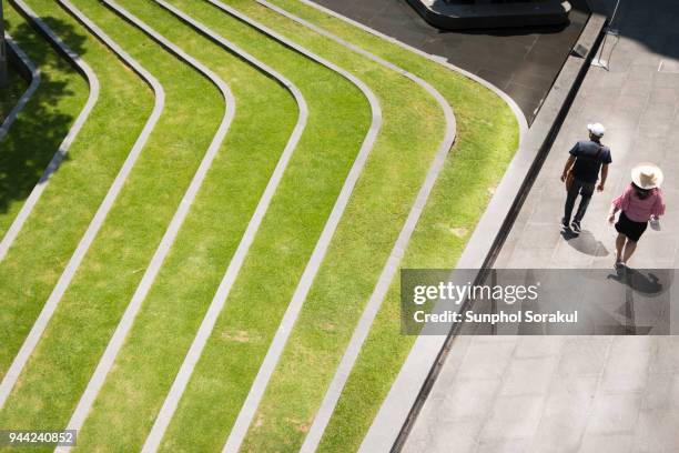 two people walking on paving beside patterned landscape - hårda material landskapsarkitektur bildbanksfoton och bilder