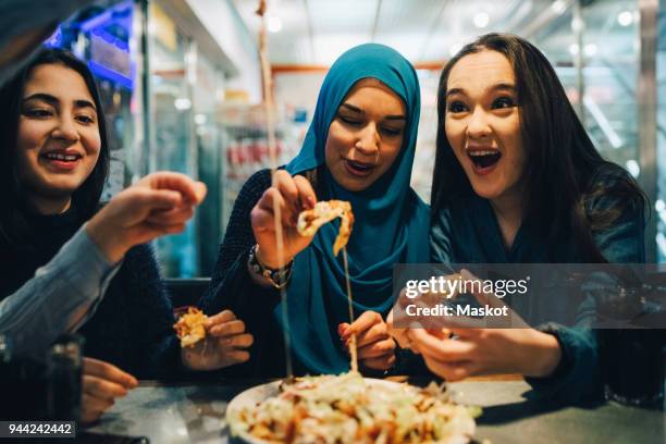 cheerful female friends eating at cafe - islam religion stock pictures, royalty-free photos & images