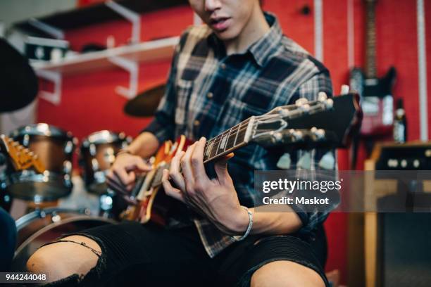 midsection of man playing guitar while sitting in recording studio - musician studio stock pictures, royalty-free photos & images