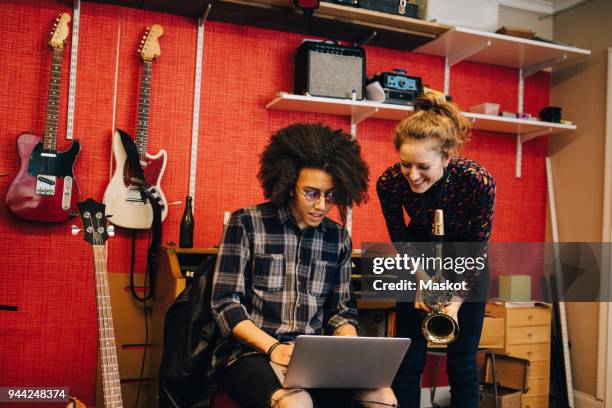 woman with saxophone looking at man using laptop while practicing at recording studio - two musicians stock pictures, royalty-free photos & images