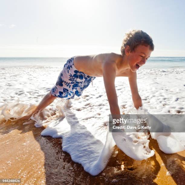 boy getting hit by wave on a beach - albufeira stock pictures, royalty-free photos & images