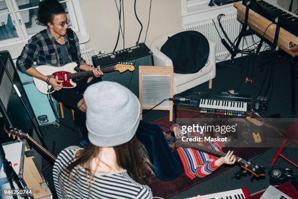 high angle view of male and female friends playing guitars while rehearsing in studio - ensayo fotografías e imágenes de stock